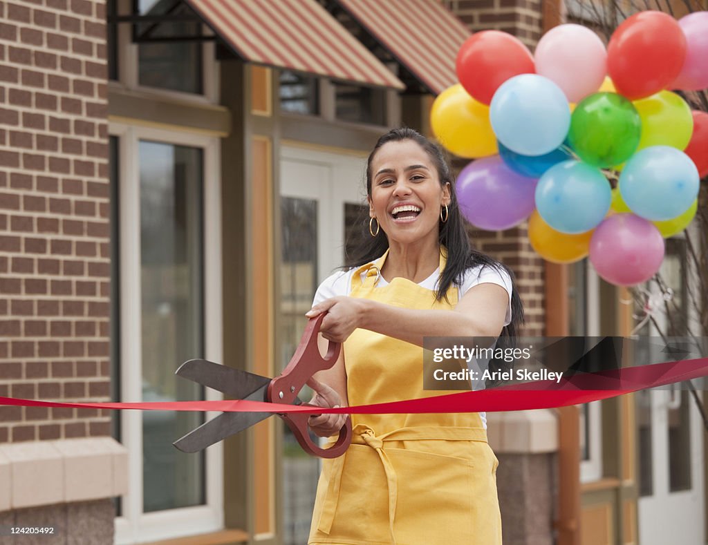 Excited business owner cutting ribbon on grand opening