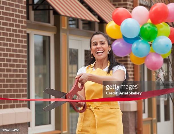 excited business owner cutting ribbon on grand opening - inaugurazione foto e immagini stock