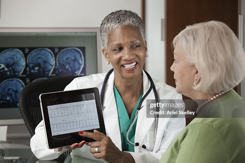 Doctor using digital tablet while talking to patient