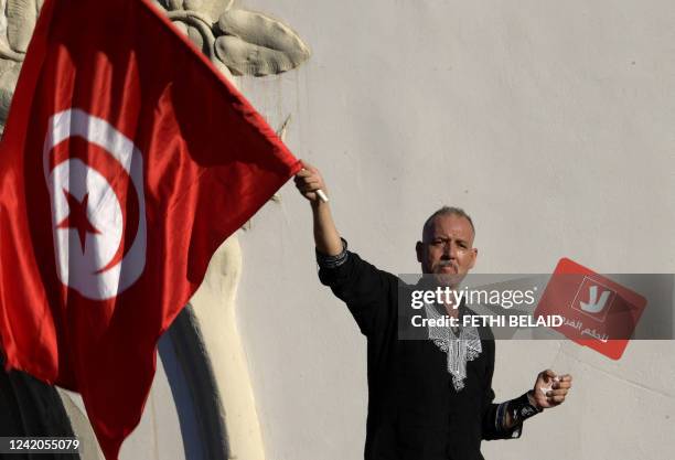 Tunisian protester raises placard and a national flag on July 22 during a demonstration along Habib Bourguiba avenue in the capital Tunis, against...