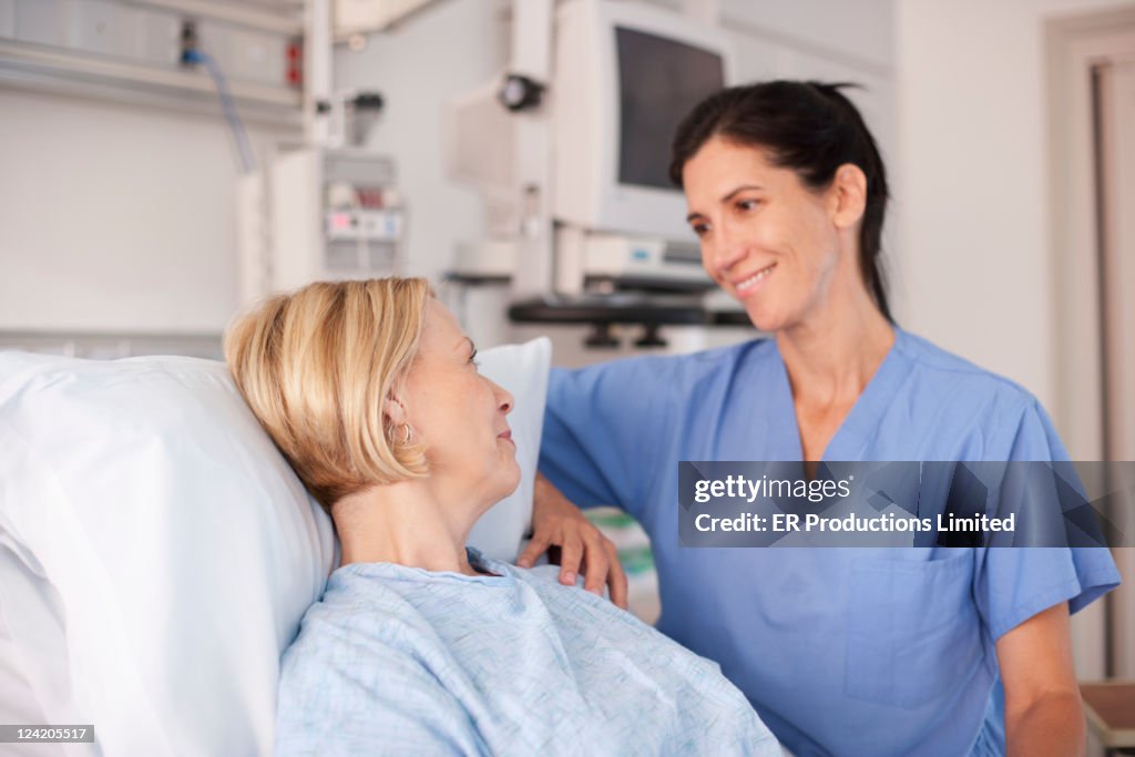 Nurse comforting patient in hospital bed