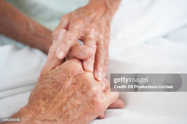 husband comforting wife in hospital bed - old couple holding hands stock pictures, royalty-free photos & images