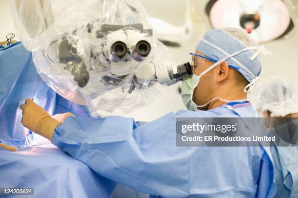 caucasian doctor operating in operating room - microchirurgie stockfoto's en -beelden