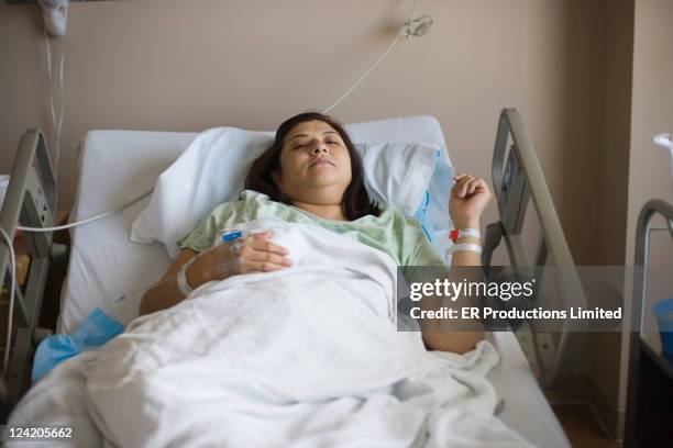 hispanic patient laying in hospital bed - brunette woman bed stockfoto's en -beelden