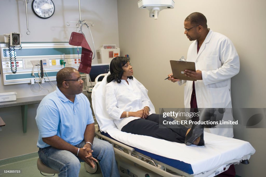 African American doctor talking to patient and her husband in hospital