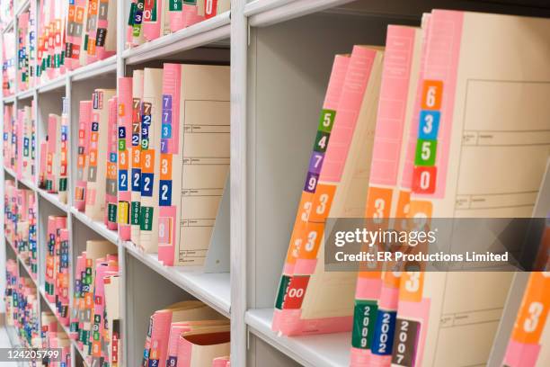 medical charts on shelf in file room - medisch dossier stockfoto's en -beelden