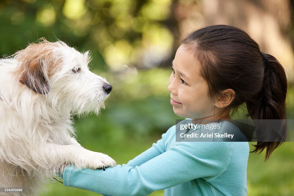 Mixed race girl playing with dog outdoors