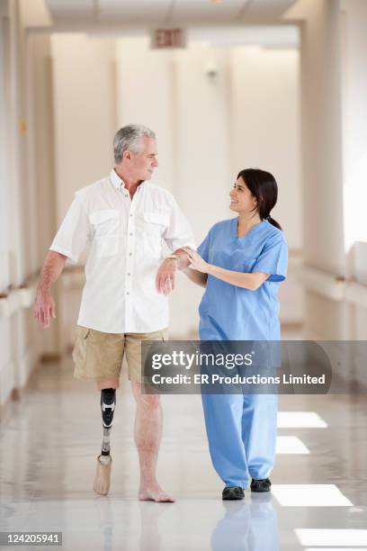 nurse supporting patient with artificial leg in hospital corridor - needs improvement stock pictures, royalty-free photos & images