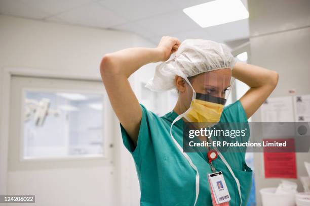 hispanic surgeon tying surgical mask - flu mask stock pictures, royalty-free photos & images