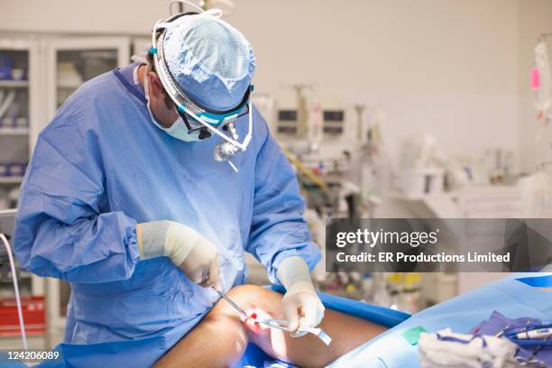 doctor operating on leg in operating room - knee stock pictures, royalty-free photos & images