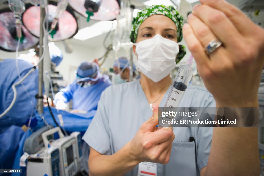 Médico encher a seringa na Sala de Cirurgia com Assistência