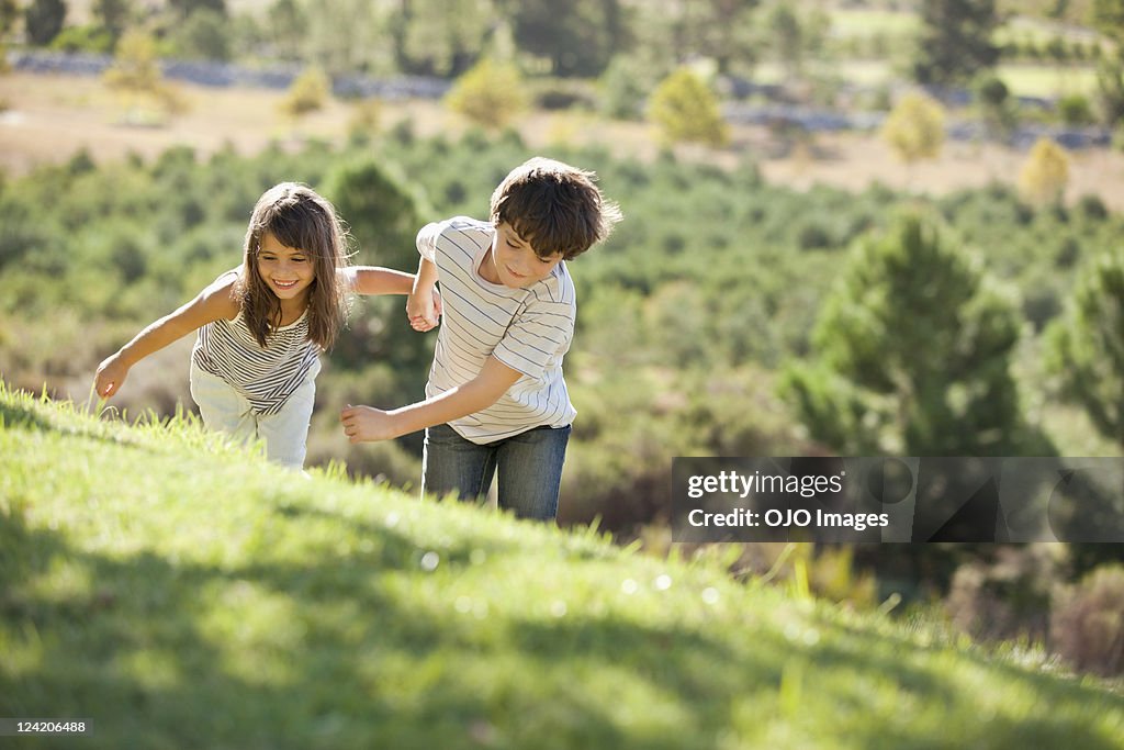 Girl running in park holding brother's hands