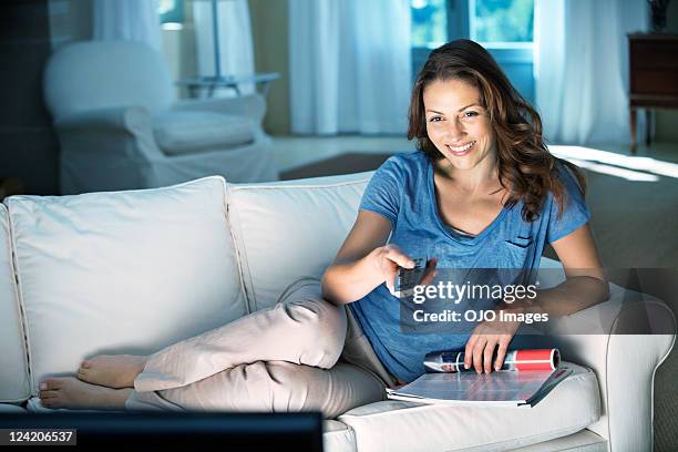 heureux détendue mid femme adulte tenant une télécommande à la maison - regarder tv photos et images de collection
