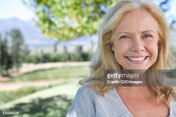 portrait of smiling mature woman in park - women wrinkle stockfoto's en -beelden