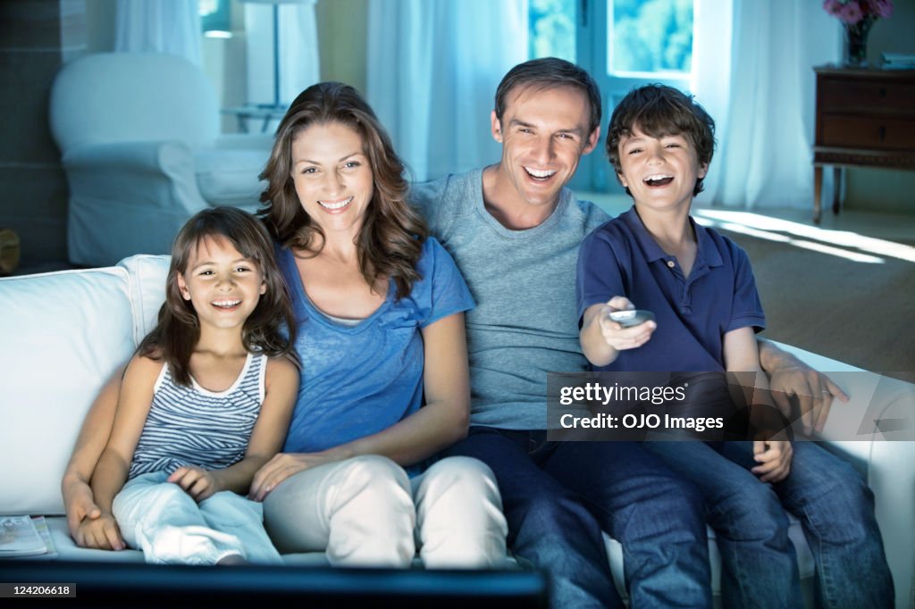 Feliz pareja con dos niños disfrutando de un televisor en su