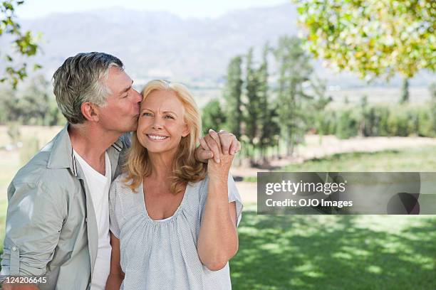 romantic couple holding hands and kissing in park - couple lust stockfoto's en -beelden