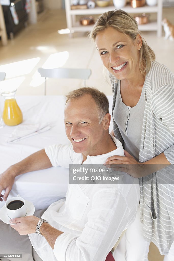 Smiling mature couple at home, man with cup of tea