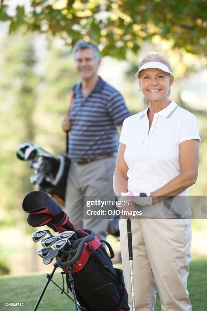 Portrait of happy couple with golf bags