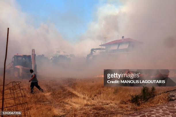 Person runs as wildfire approaches houses on Vatera coastal resort on the eastern island of Lesbos on July 23, 2022. Residents were evacuated as the...