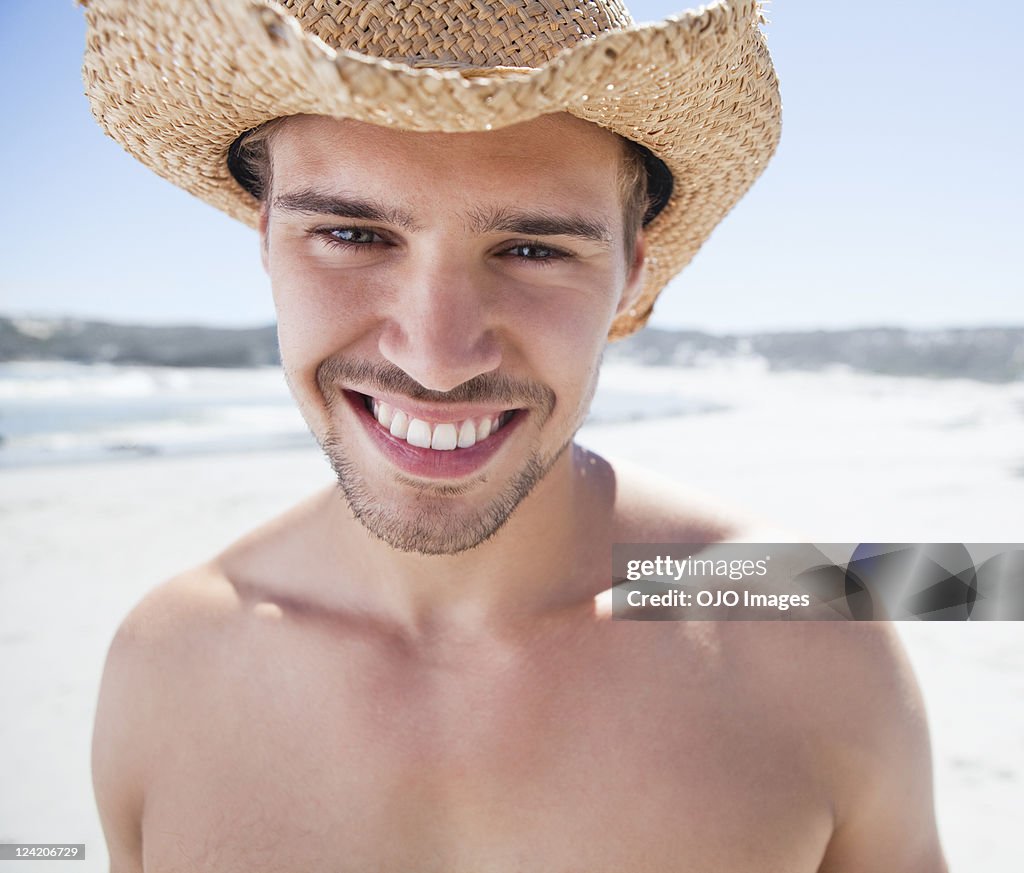 Primer plano de una hermosa joven sonriente usando sombrero en la playa