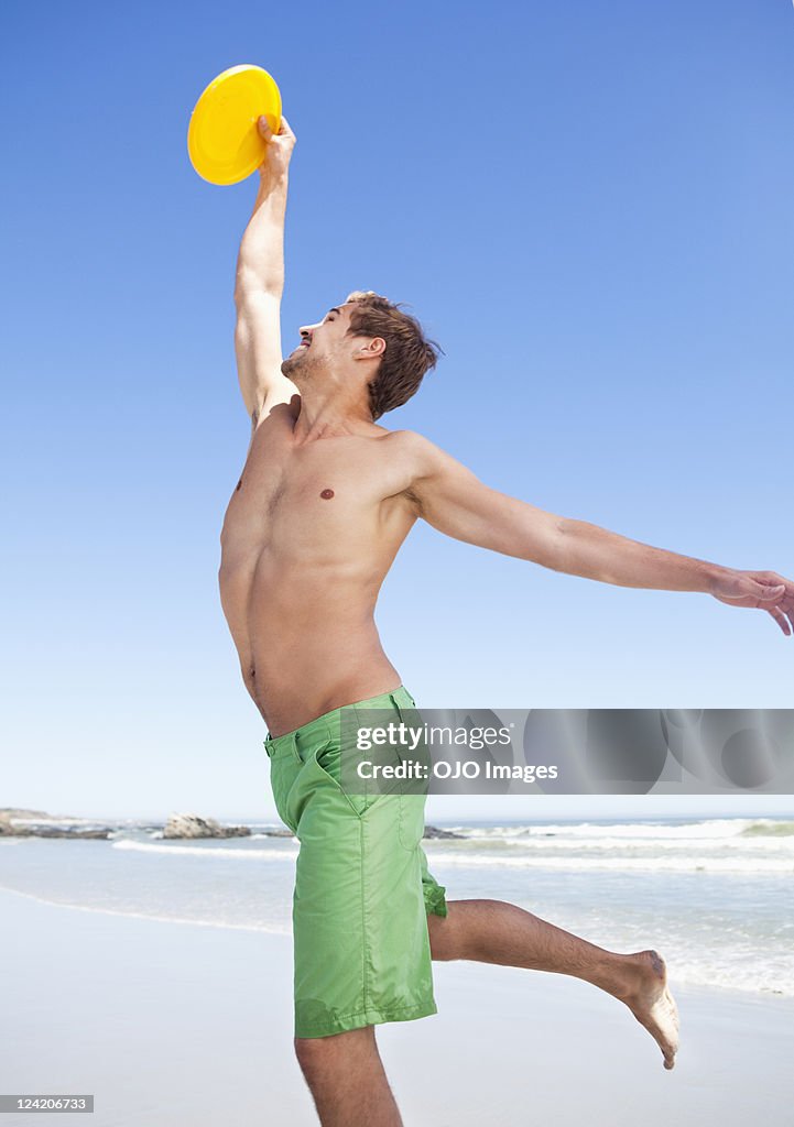 Young man catching frisbee on beach