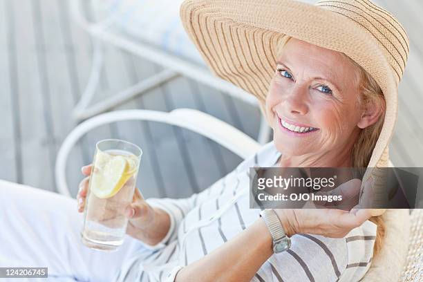 portrait of happy senior woman having a glass of lemonade - sun hat stock pictures, royalty-free photos & images