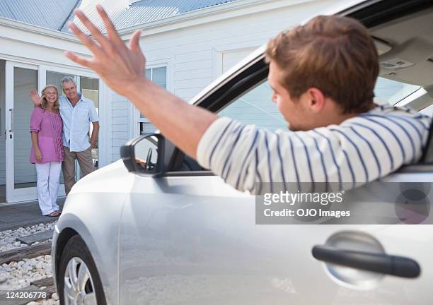 giovane uomo in auto di partenza per i genitori - sventolare la mano foto e immagini stock