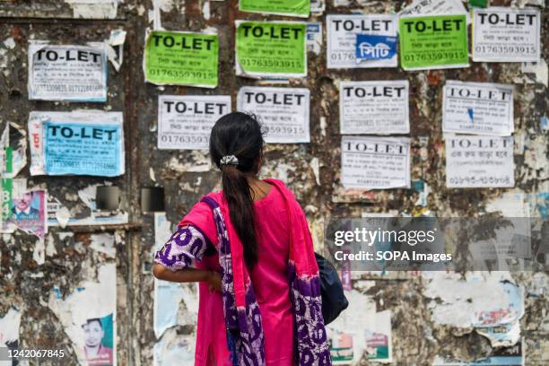 Woman is looking at To-Let signs on a wall in Dhaka.