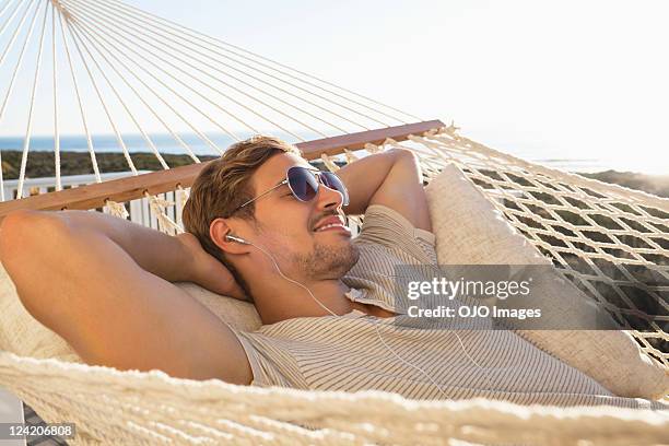 young man listening music and relaxing in hammock - young man listening music and relaxing in hammock stock pictures, royalty-free photos & images