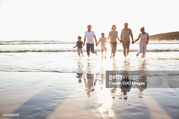 familie holding hände in wasser am strand - day 6 stock-fotos und bilder