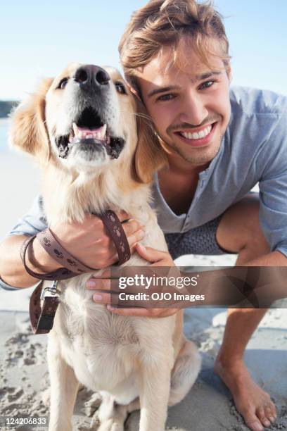 ritratto di un sorridente giovane uomo con cane in spiaggia - ragazzo con cane foto e immagini stock