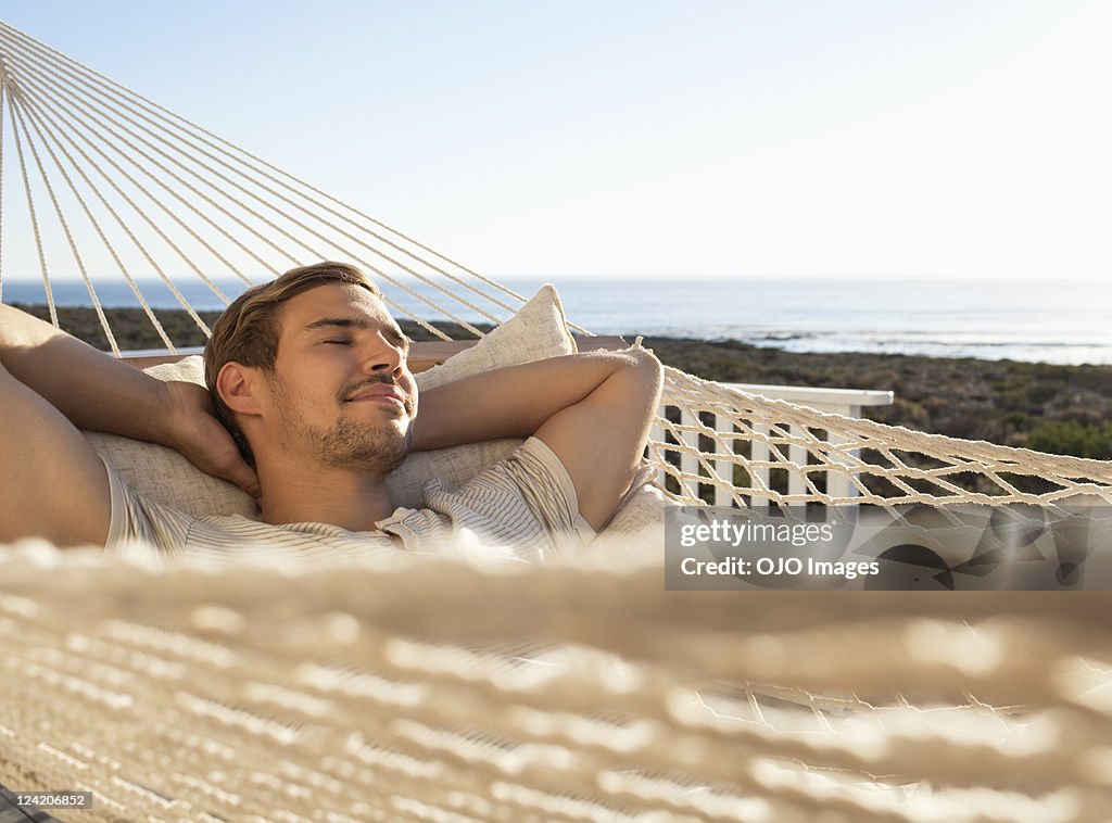 Young man relaxing in hammock with eyes closed