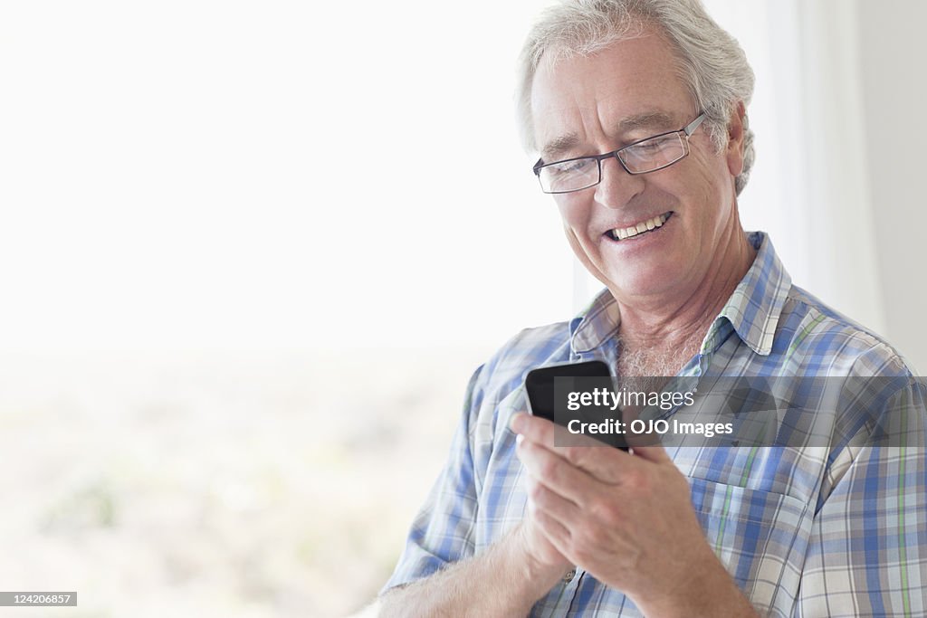 Smiling senior man texting using smart phone