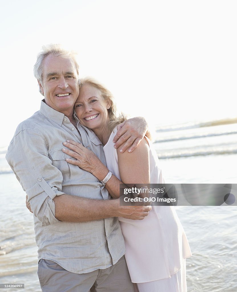 Portrait of a cheerful couple hugging on beach