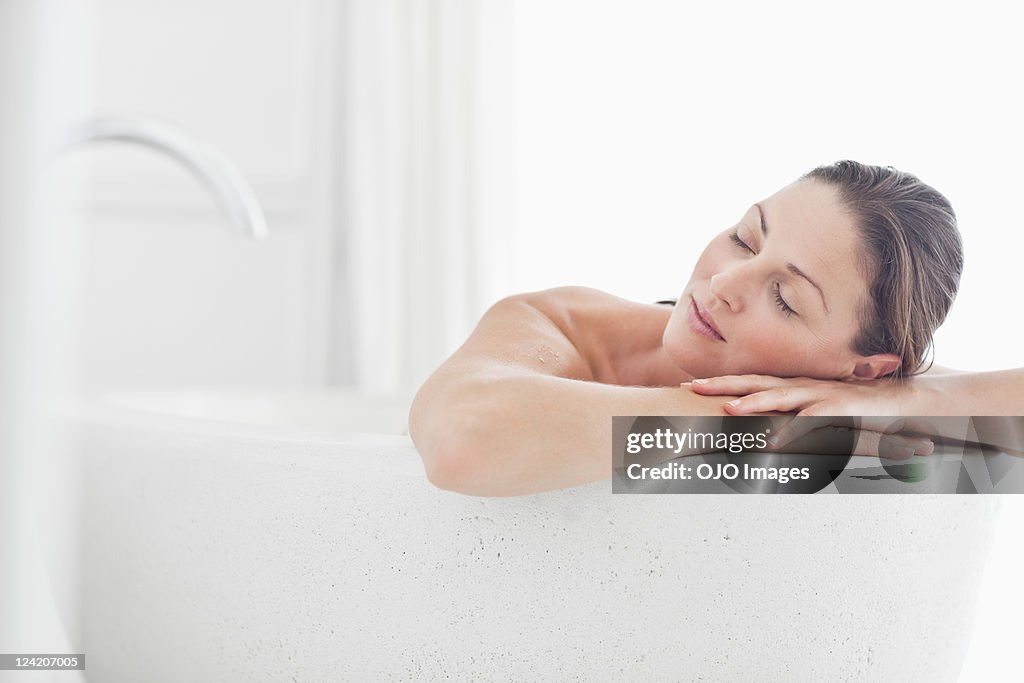 Close-up of beautiful mid adult woman relaxing in bathtub with eyes closed