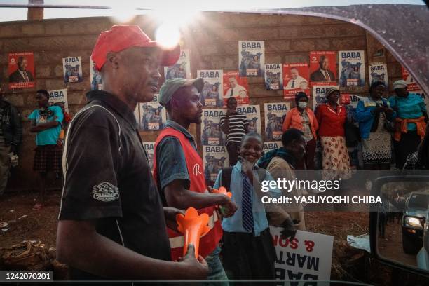 Supporters walk past campaign posters after Azimio La Umoja Coalition presidential candidate Raila Odinga's campaign rally in Murang'a on July 23...