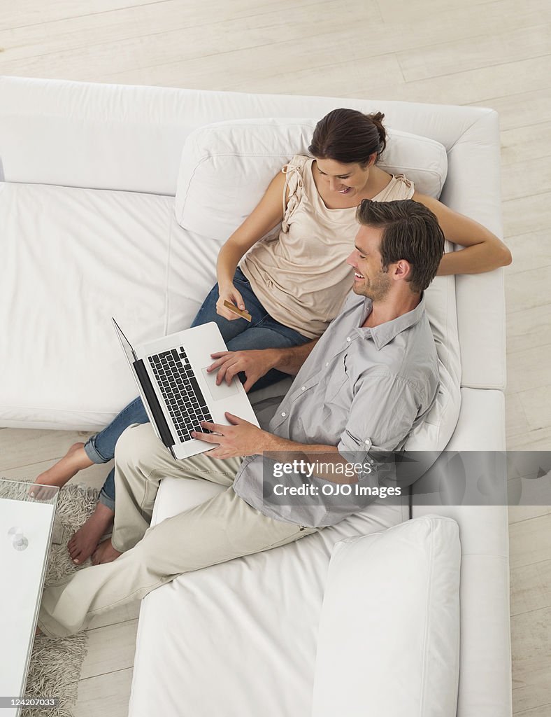 High angle view of smiling mid adult couple working on laptop, shopping online