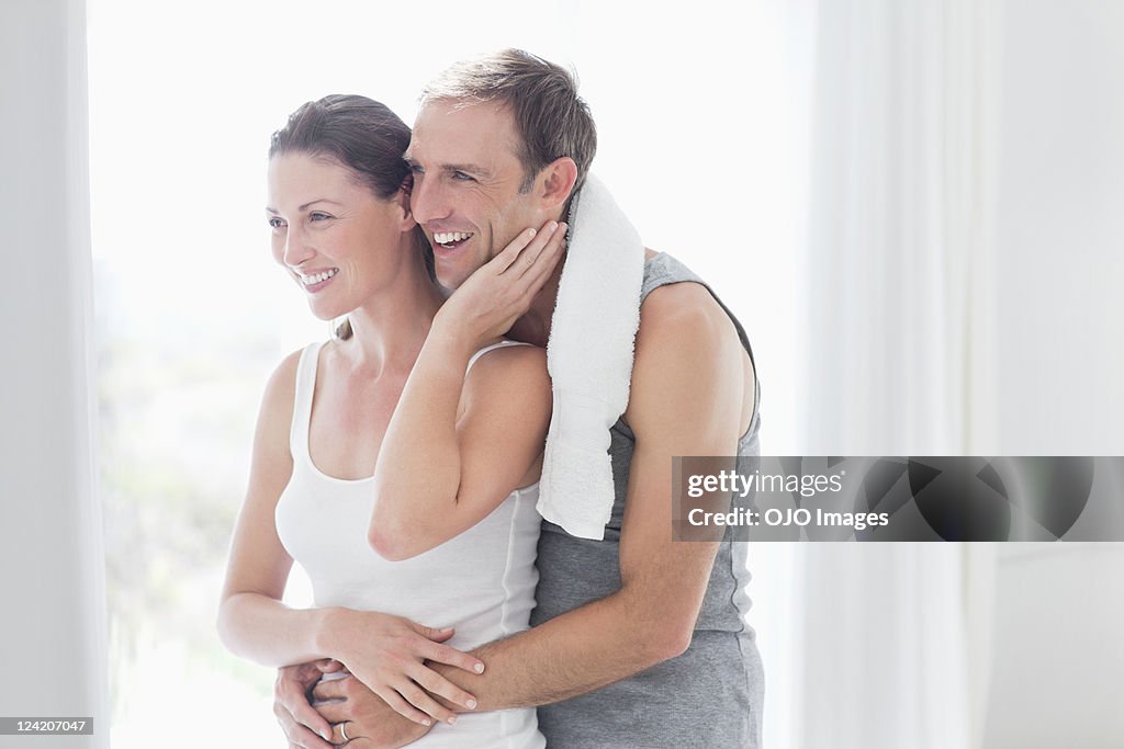 Handsome mid adult man embracing woman at home