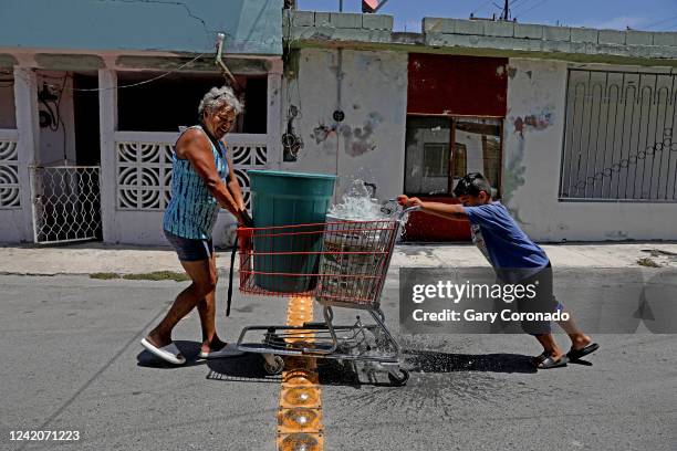 Alma Limon and grandson Mateo Chavez push a shopping cart of not potable water delivered by a tanker truck in the scorching heat in Colonia Nuevo...