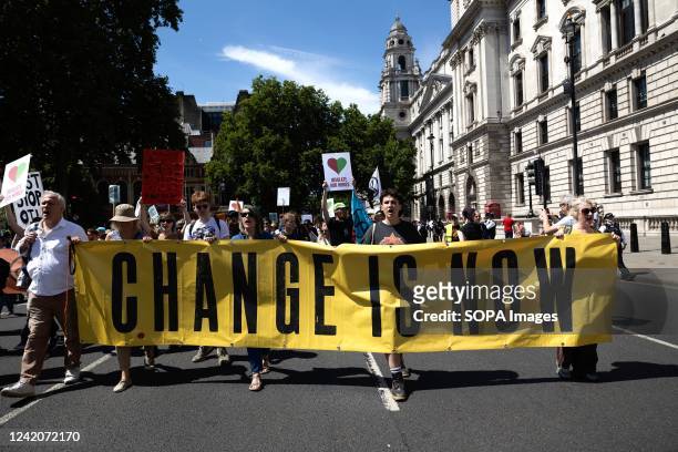 Group of activists hold a banner while marching to Parliament Square. Multiple climate activists groups, including Just Stop Oil, Insulate Britain...