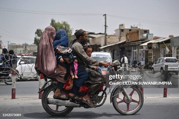 Man rides on a motorbike with two burqa-clad women and children in Kandahar city on July 23, 2022.