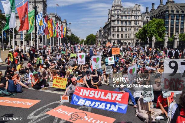 Protesters holding various banners and placards sit and block the road during the demonstration in Parliament Square. Protesters from Just Stop Oil,...