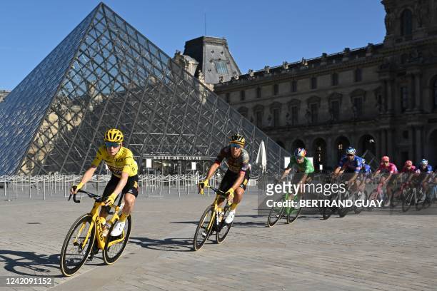 Jumbo-Visma team's Danish rider Jonas Vingegaard , wearing the overall leader's yellow jersey cycles past the Louvre Pyramid, designed by Chinese...