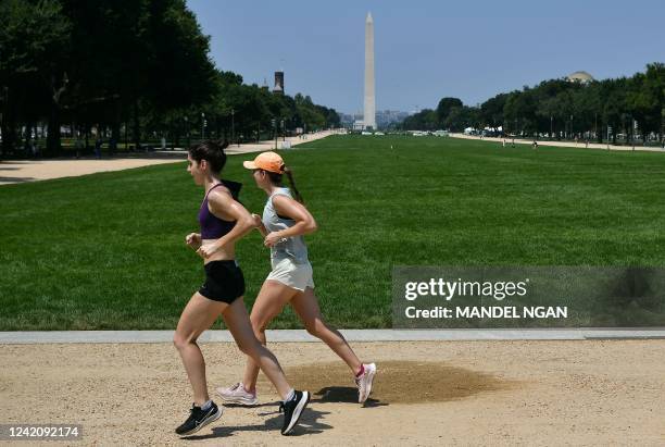 Runners on the Mall are jog in front of the Washington Monument in Washington, DC on July 24, 2022. - The heat wave blanketing the region is expect...