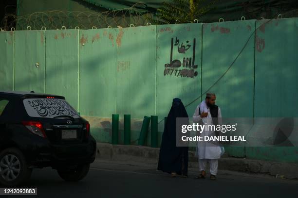 Woman wearing a burqa-clad walks with a man in Kabul on july 24, 2022.