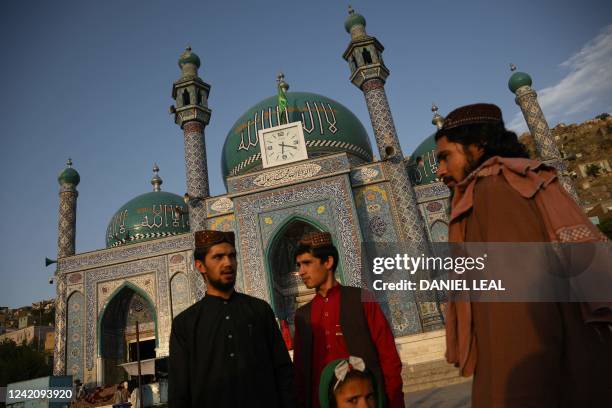 Taliban and shi'ites stand in front of the the Sakhi Shah-e Mardan Shrine and mosque in Kabul on july 24, 2022. - The shrine is visited mainly by...