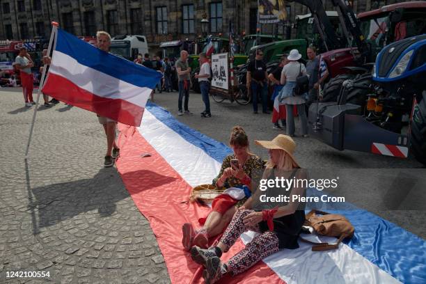 Protesters sit on a large Dutch flag as agricultural and transport workers affiliated to far-right and conspirationalist parties gather on the Dam...