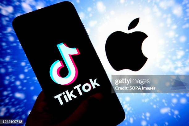 In this photo illustration, a Tiktok logo seen displayed on an android smartphone with an Apple logo in the Background.