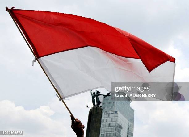 An Indonesian protestor waves a national flag during a demonstration against an alleged conspiracy that has shocked the nation in Jakarta on November...