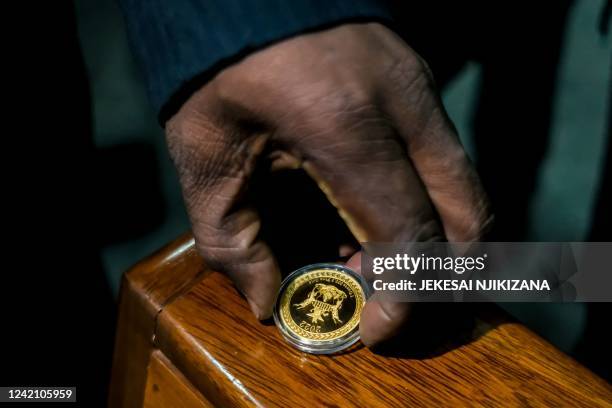 Zimbabwe Reserve Bank governor displays the country's new "Mosi-oa-Tunya" gold coin in Harare on July 25, 2022. - The new coin which weighs 1oz is...